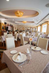 un comedor con mesas blancas y sillas blancas en Hotel Atlantis Medical, Wellness & Conference, en Hajdúszoboszló