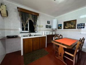 a kitchen with a table and a sink and a table and chairs at Alojamento Vila Flor in Praia da Vitória