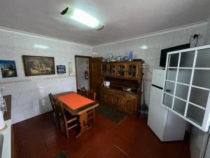 een keuken met een tafel en een koelkast bij Alojamento Vila Flor in Praia da Vitória