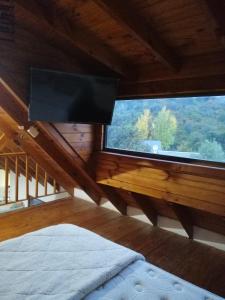een slaapkamer met een groot raam en een flatscreen-tv bij Depto en Villa Pehuenia in Villa Pehuenia