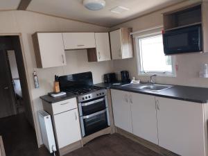 a small kitchen with a stove and a sink at Up on the hill - On a park with a lake in Westfield