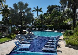 a pool with chaise lounges and lounge chairs at Wembley Inn Hotel in Ubatuba