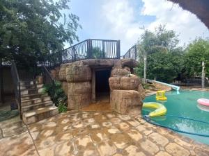 a backyard with a pool with a rock cave and a slide at Clyde's on Dale Guest House in Springs