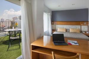 a bedroom with a bed and a desk with a laptop at Embajador Hotel in Buenos Aires