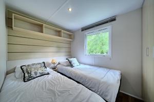 Duas camas num pequeno quarto com uma janela em Chalet 2 em Salies-du-Salat
