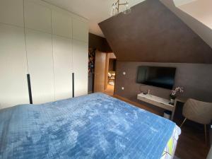 um quarto com uma cama azul e uma televisão em Grand Vista Apartman em Palić