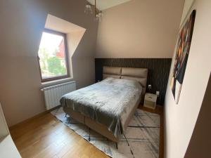 um pequeno quarto com uma cama e uma janela em Grand Vista Apartman em Palić