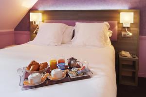 un vassoio di cibo su un letto in una camera d'albergo di Hôtel Poussin a Parigi