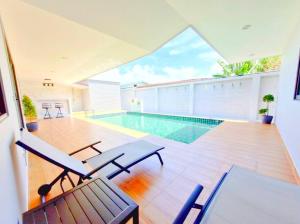 a swimming pool in a house with chairs and a table at Pool Villa Rawai in Ban Saiyuan (1)