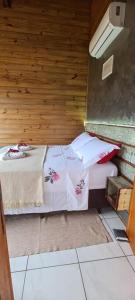 a small bedroom with a bed in a wooden wall at Moradas do Maneca in Imbituba