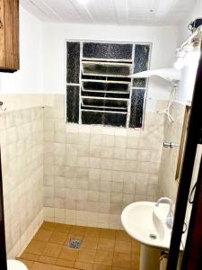 ein Bad mit einem Waschbecken und einem Fenster in der Unterkunft Casa amarela in Juiz de Fora