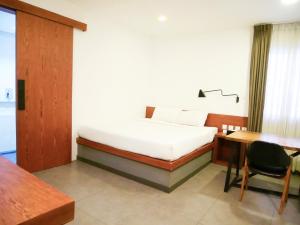 a bedroom with a bed and a desk and a table at Cheers Social Apartment & Hotel in Phnom Penh