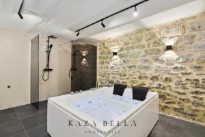 La salle de bains est pourvue d'une baignoire et d'un mur en pierre. dans l'établissement KAZA BELLA - Maisons Alfort 5 Luxurious apartment with private garden and Jacuzzi, à Maisons-Alfort