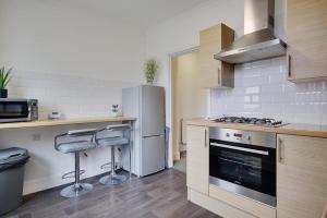 a kitchen with a refrigerator and two bar stools at Wimbourne Road Apartment 3 in Bournemouth