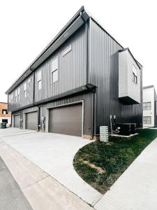 a black building with two garage doors and a sidewalk at New Luxury Townhome in Youngsville