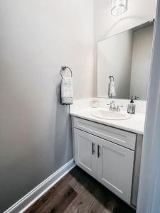 a white bathroom with a sink and a mirror at New Luxury Townhome in Youngsville