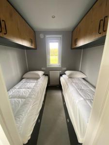 2 camas en una habitación pequeña con ventana en Chalet Rustique, en Oldeberkoop