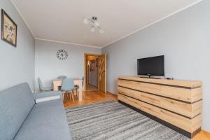 a living room with a couch and a television on a dresser at Fala 2 by Grand Apartments in Gdańsk