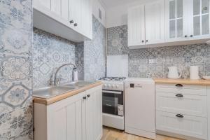 a kitchen with white cabinets and a sink at Fala 2 by Grand Apartments in Gdańsk