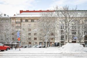 una calle cubierta de nieve con un gran edificio y coches en WeHost Spacious 2BR in the Helsinki Center en Helsinki