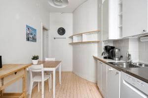 una cocina blanca con mesa y sillas. en WeHost Spacious 2BR in the Helsinki Center en Helsinki