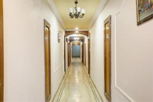 a hallway with a long corridor with white walls and a chandelier at Collection O Hotel Sunbeam in Gwalior