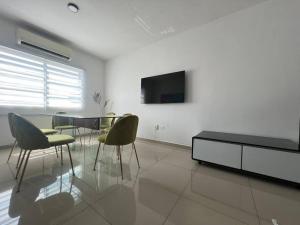 a living room with a table and chairs and a tv at Departamento Torres Mina Residencial in Villahermosa