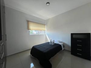 a bedroom with a black ottoman and a television at Departamento Torres Mina Residencial in Villahermosa