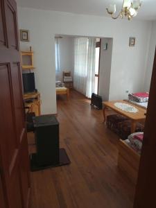 een woonkamer met een houten vloer en een tafel bij Family Hotel Shisharka in Batak