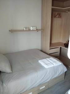 um pequeno quarto com uma cama com lençóis brancos em Apartamento Centro em Montoro