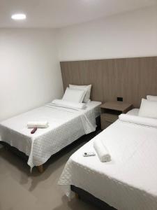 two beds in a room with white sheets and towels at Hotel Ocean Boutique Maicao in Maicao