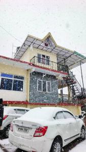 a white car parked in front of a house in the snow at Abhi house in McLeod Ganj
