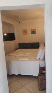 a bedroom with a white bed with a tv on the wall at Pousada Cantinho D'Abrantes in Ilhabela