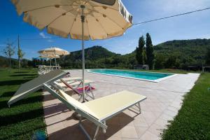un patio con sombrilla, sillas y piscina en Agriturismo Verziere, en Fermignano