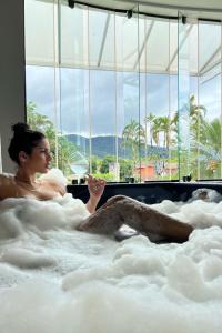 una donna sdraiata in una vasca da bagno con vista di Wembley Inn Hotel a Ubatuba