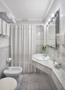 a white bathroom with a toilet and a sink at Hotel Impala in Buenos Aires