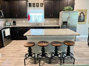 a kitchen with a island with stools and a refrigerator at Sweet Stay with fully fenced yard in Sanford