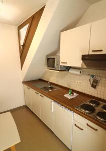 a small kitchen with white cabinets and a sink at Apartment 17 - Ferienresidenz Roseneck, Galeriewohnung, mit Schwimmbad in Todtnauberg bei Feldberg in Todtnauberg