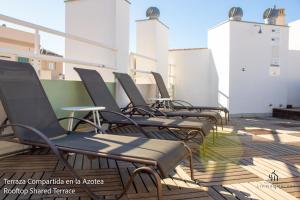 una fila de sillas sentadas en la parte superior de un edificio en Living4Malaga Suites Superior, en Málaga