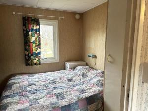 um pequeno quarto com uma cama e uma janela em Nice cottage located in Sandvik, 100 meters from a bay em Hagby