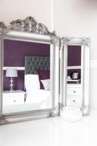 a mirror in a room with a bed and a lamp at The Berburry in Torquay