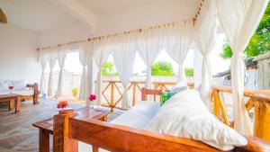 a bedroom with a wooden bed with white curtains at Villa Clarida in Watamu