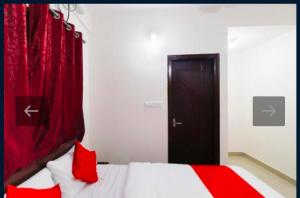 a bedroom with a bed with red pillows and a door at Hotel Prakrathi Residency in Bangalore