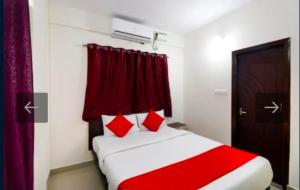a bedroom with a bed with red and white sheets and red curtains at Hotel Prakrathi Residency in Bangalore