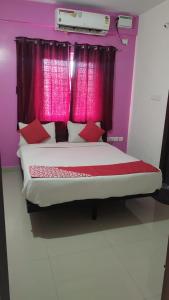 a bedroom with a bed with a pink window at Hotel Prakrathi Residency in Bangalore