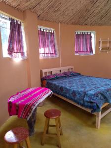 a bedroom with two beds and a chair and windows at Tony's House Eco Hostel in Huaraz