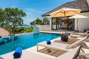 a pool with chairs and umbrellas next to a house at VIlla Tramonto sunset seaview villa Koh Samui in Koh Samui