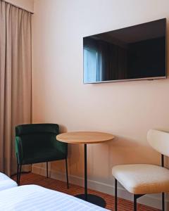 a room with a table and two chairs and a tv at Hôtel L'Ours De Mutzig in Mutzig