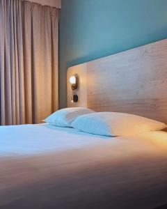 a bedroom with a bed with white sheets and pillows at Hôtel L'Ours De Mutzig in Mutzig