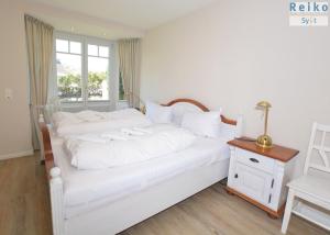 een slaapkamer met een wit bed met witte kussens bij Syltrose Whg 2 in Westerland